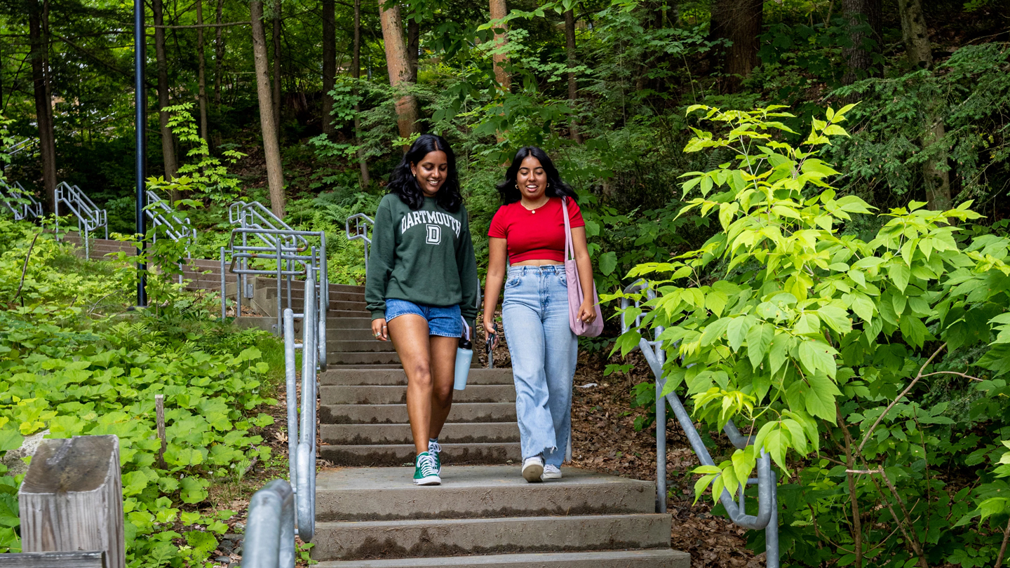 A photo of two students chatting while walking down an outside staircase