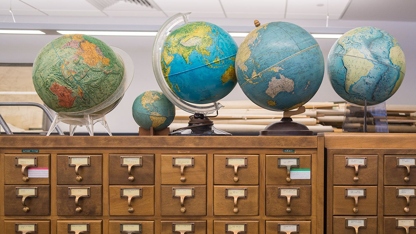 A photo of globes atop a library card catalog