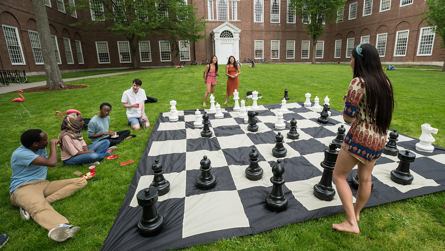 Photo of students playing on an over-sized chess board in front of Baker Library