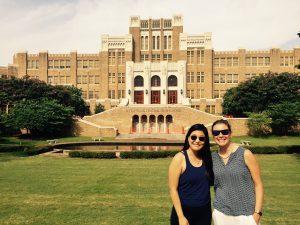 two women stand in front of historic school building