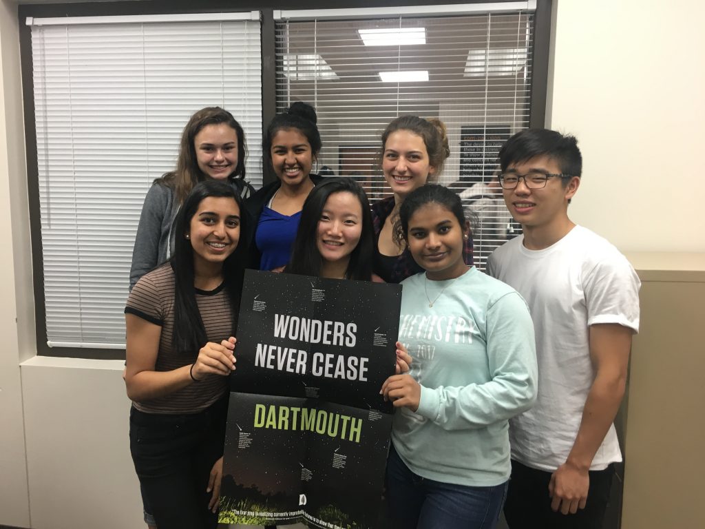 Seven high school students pose with a Dartmouth poster