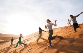 A photo of students racing down the sand dunes of the Namib