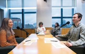A photo of Samantha Palermo '24 and Mac Mahoney '26 talk as StoryCorps staffers Stephanie Glaros and Diane Bezucha facilitate and recording the conversation