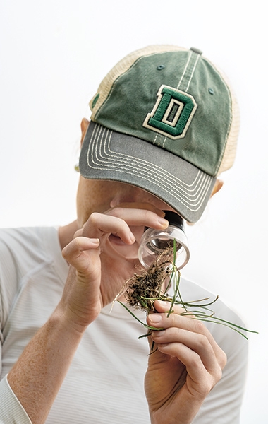 A photo of a student studying grasses and soil under a loop 