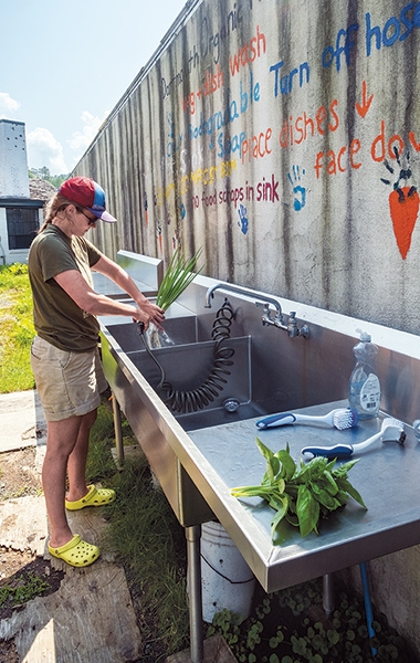 A student washes freshly-picked vegetables at the outdoor sinks at the Dartmouth Organic Farm