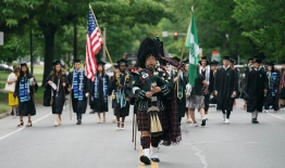 A photo of Joshua Marks '96 leading the Class of 23 Commencement procession toward the Green