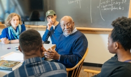 A photo of students and a professor having a discussion in a classroom