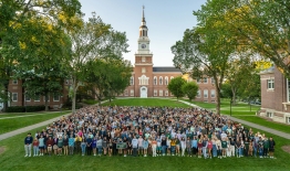 A photo of members of the Class of 2025 standing on the green lawn in front of Baker-Berry Library