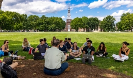 A photo of a professor holding class on the Green with Baker Tower in the background