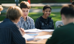 A photo of students sitting around a table outside participating in a class
