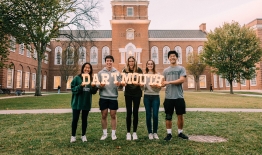 A photo of a group of students on the front lawn of Baker-Berry Library holding up light-up letters that spell out Dartmouth