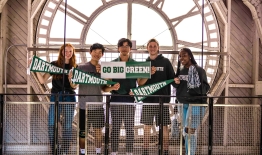 A photo of students holding pennants and banners inside the clock tower of Baker Tower