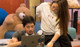 A photo of two students looking at a laptop