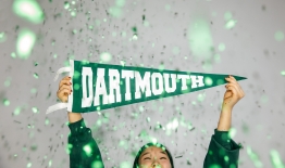 a photo of a student holding a Dartmouth pennant with glitter falling around her