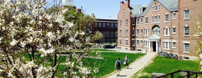 Photo of students walking on a sidewalk behind Baker Library