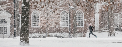 A photo of snow in front of Sanborn and a person running