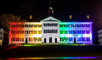 A photo of Dartmouth Hall lit up with rainbow lights for PRIDE