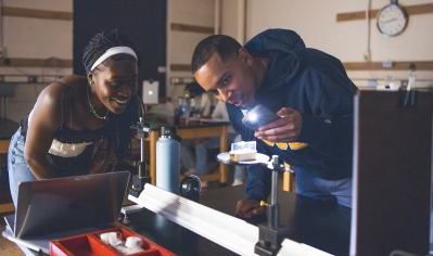 Mirelle Mah'moud '25 and Justin Santana '25 photograph the laser point they beamed through copper wire during physics lab