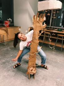 girl behind cardboard sculpture of a hand