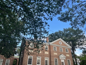 A photo of Sanborn Library with trees in the foreground and a blue sky in the background.