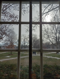 Fall scenery behind a white window frame: rain and students walking to class