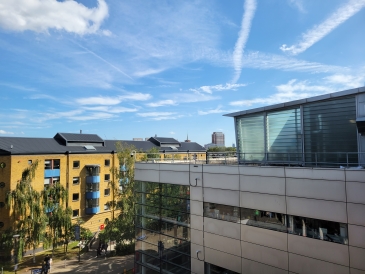 A yellow brick building on the left and a modern glass building on the rigth under a clear, blue sky.