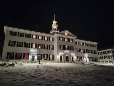 Dartmouth Hall: A big white building with dim lighting at night with snow.