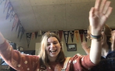 A photo of me in a college counseling office with my hands up and tears in my eyes. My friend is clapping his hand, but is blocked by my hand.