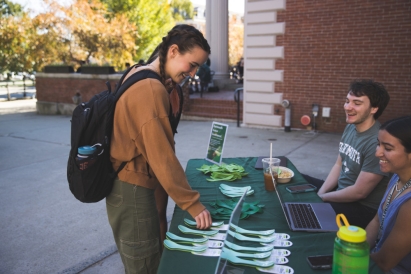 Emma Bonz '25 picks up free sporks from Student Body president David Millman '23 and Vice President of Dartmouth Student Government Jessica Chiriboga '24 outside Collis.