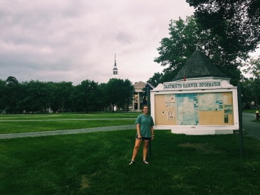 Abbi standing in front of a map on the green, with Baker Berry in the background