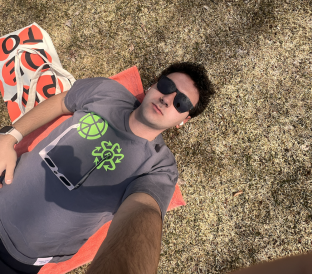Blogger laying on the green with their glasses on, enjoying the sun's warmth..