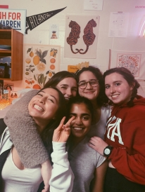 Abbi and 4 friends smiling in a dorm room with decorations in the background.