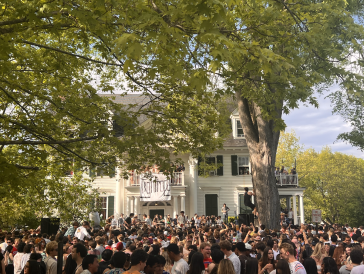 Picture of a crowd of students listening to live music on a sunny day.