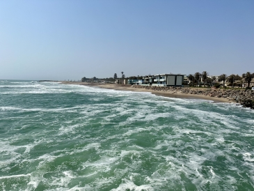 A horizontal photo of the blue water meeting the beach town of Swakopmund