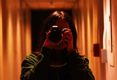 Photograph of a girl holding a camera taking a photograph. 