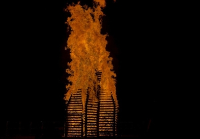 Bright orange flames of the bonfire against a dark sky