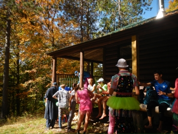  Dartmouth Students dressed in colorful flair gather around a cabin to support hikers for the Fifty.