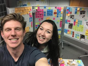 Colleen and her project partner, Matt, taking a selfie in front of their post-it note filled white boards