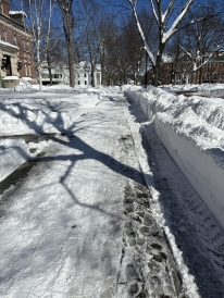 A photo of a sidewalk at Dartmouth covered in snow. There are two feet of snow shoveled off to each side of the path.