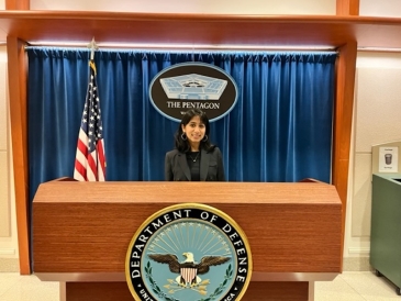 Rujuta '24 standing in front of podium at the Pentagon
