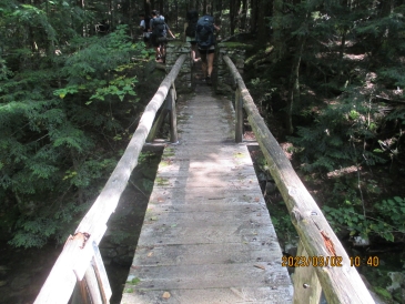 hiking over a bridge that has rock 'pillars' at the ends