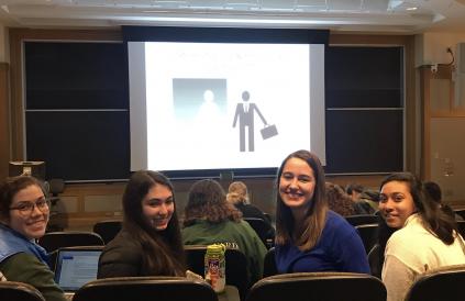 four women in lecture hall before power point slide