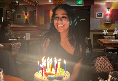 A picture of a Dartmouth Student in a restaurant, behind a cake with candles