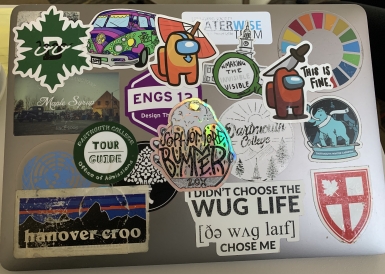 A silver MacBook Pro covered with various stickers. 
