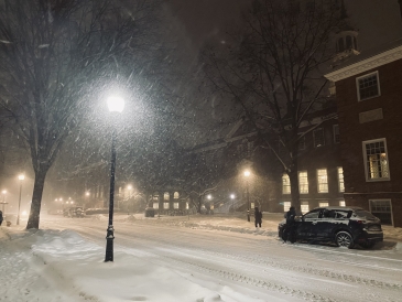 One of Dartmouth's brick dorms during a winter storm at night with a streetlight shining