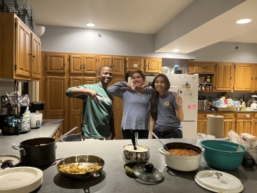 An image of three people standing behind dishes of food on a table