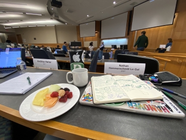 A view of a Dartmouth business classroom with an open notebook and plate of fruit.