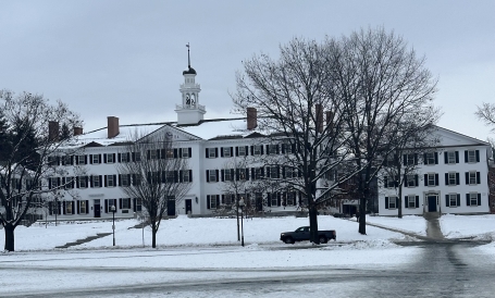 A picture of Dartmouth Hall, a white building, while there is a lot of snow surrounding the area.