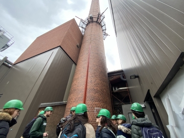 a picture of several students huddled around Dartmouth's iconic smokestack, extending far into the sky