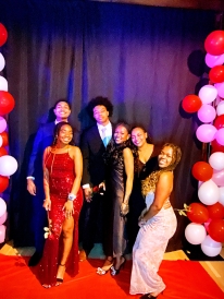 My friends and I standing in front of a pink backdrop with balloons at our gala.